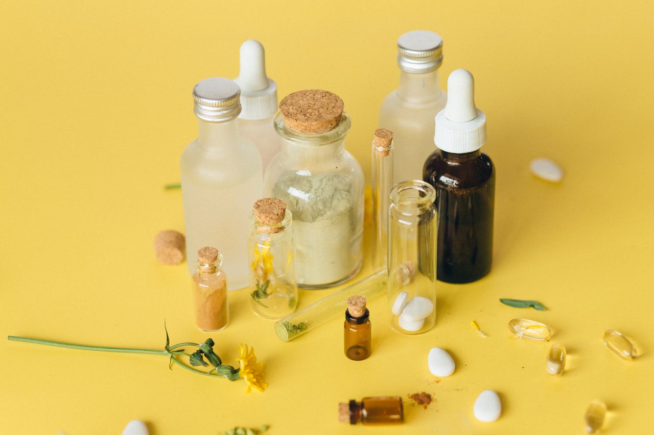 Home Assorted bottles and herbs showcasing natural medicine on a vibrant yellow surface.